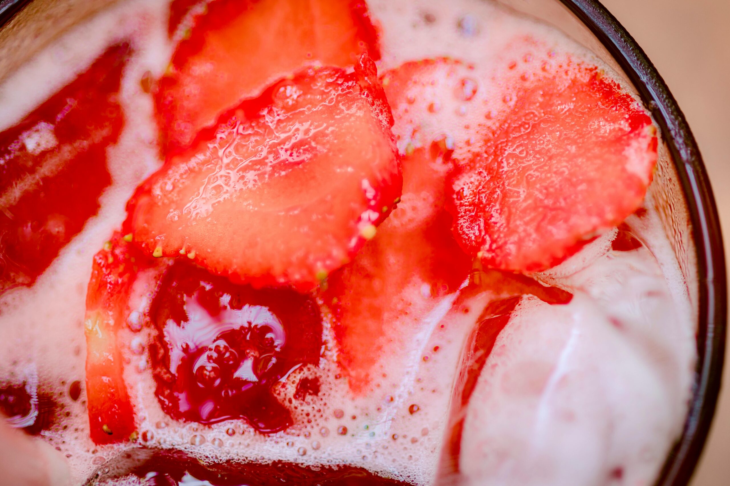 Close-up of sliced strawberries in a bubbly, refreshing drink.